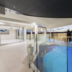 Pool and deck in modern mansion at dusk.